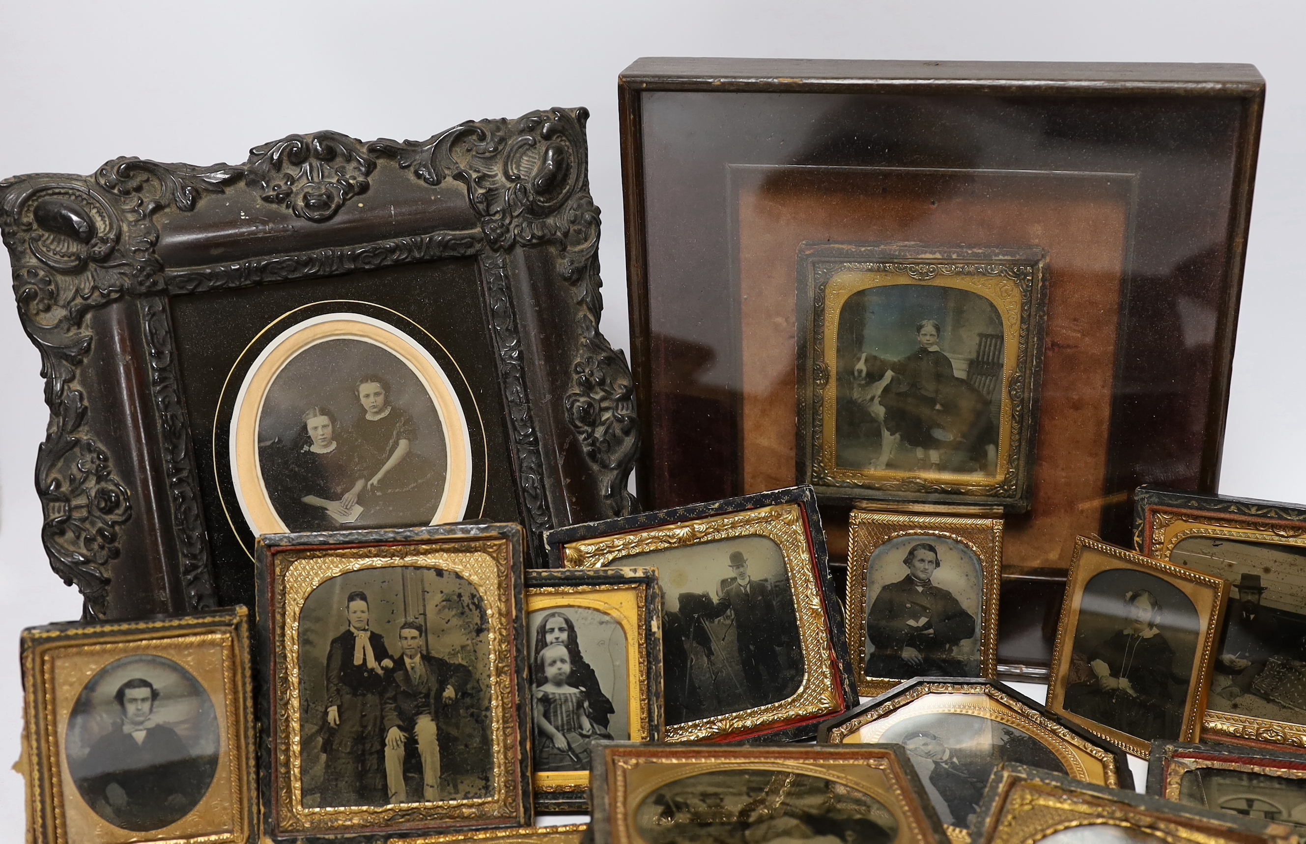 A collection of mid 19th century ambrotype portrait photographs, all mounted in brass etc frames, some in decorative cases, two examples framed (25)